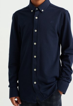 Camicia blu navy con bottoni in tessuto morbido, caratterizzata da un colletto classico, chiusura con bottoni e un piccolo logo ricamato sul petto.