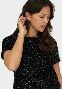 Schwarzes Paillettenoberteil mit kurzen Ärmeln, rundem Ausschnitt und strukturiertem Obermaterial. Der glatte Stoff hebt die glänzenden Pailletten hervor.