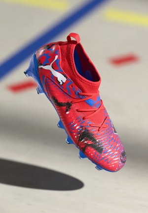 Botte de football rouge avec des accents bleus, tige texturée et motifs graphiques. Présente un col de style chaussette et une semelle à crampons pour une meilleure adhérence.