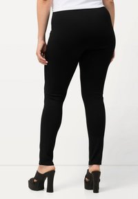 Zwarte leggings van rekbare stof, met een aansluitend ontwerp en een gladde textuur. Draag ze met zwarte hoge hakken.