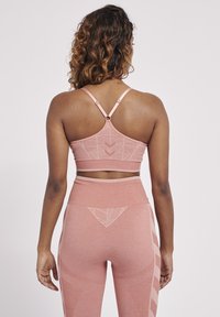 Rosa sportbh och högmidjade leggings gjorda av strukturtyg, med geometriska mönster och justerbara axelband.