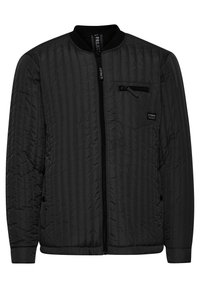 Giubbotto bomber trapuntato nero con chiusura a zip, colletto a coste e tasca sul petto con zip. Texture liscia con cuciture verticali.