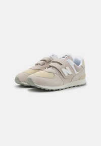 Baskets beige clair et crème en matériaux mesh et daim, avec des bandes Velcro, des semelles texturées et un logo 'N' sur le côté.