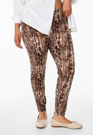 Dierlijke print leggings in bruin- en zwarttinten, met een gestructureerd ontwerp. Draagt men bij een witte shirt en lichte, platte schoenen.