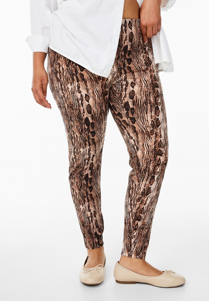 Dierlijke print leggings in bruin- en zwarttinten, met een gestructureerd ontwerp. Draagt men bij een witte shirt en lichte, platte schoenen.