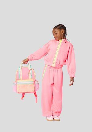 Roze sportoutfit met een jas met ritssluiting en broek met elastische taille, gecombineerd met een levendige roze en pastelrugzak met mesh-details.