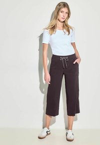 Helles blaues T-Shirt mit kurzen Ärmeln, kombiniert mit dunkelgrauen, kurzen Hosen, die einen elastischen Bund und einen Kordelzug haben sowie Seitentaschen.
