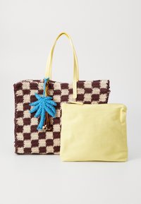Borsa a tote intrecciata con motivo a quadri marrone e crema, dotata di manici gialli. Presenta un ciondolo a forma di palma blu; include una pochette gialla con zip.