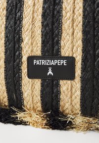 Borsa in paglia intrecciata con strisce nere e beige naturale, caratterizzata da una superficie testurizzata e una toppa rettangolare nera con logo.