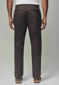 Chinos marron avec un design à jambe droite, en mélange de coton, dotés de deux poches arrière avec des fermetures à bouton et d'une taille plate.