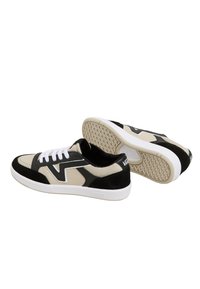 Black and beige sneakers with suede and canvas materials, featuring white laces, a textured rubber sole, and a prominent logo on the heel.