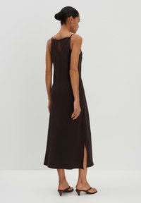 Schwarzes ärmelloses Kleid mit einem Rückenausschnitt in Schlüssel-Form, seitlichem Schlitz und entspannter Passform, aus weichem Stoff mit glatter Textur.