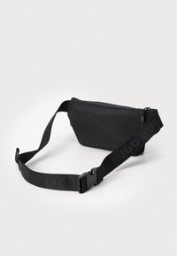 Sac à taille en nylon noir de forme rectangulaire, avec fermeture éclair et sangle réglable ornée de marquage en relief. Texture lisse, design compact.