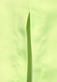 Țesătură verde lime cu o textură netedă, având o cusătură și un detaliu cu slit vertical, evidențiind simplitatea în design.