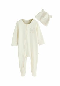 Kremasto obarvan dojenčkov pajac iz mehke tkanine, z zadrgo spredaj, dolgimi rokavi, pokritimi nogicami in ujemajočo kapo z medvedjimi ušesi.