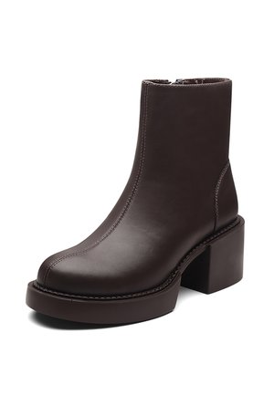 Bota de cuero marrón para el tobillo con tacón grueso, punta redondeada, costuras visibles y textura suave. Cremallera lateral para facilitar el uso.