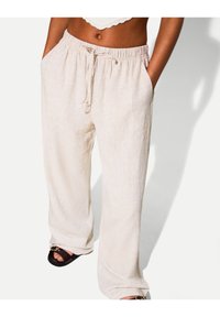 Ljust beige linnebyxor med ett elastiskt midjeband och dragsko; har sidofickor och en avslappnad passform. Mjuk textur och vida ben.