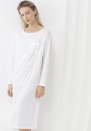 Weißes, langärmliges Kleid aus weichem Stoff mit rundem Halsausschnitt, Seitenschlitzen und einer Brusttasche. Das Design ist schlicht und locker geschnitten.