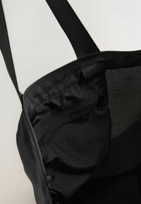 Melnas tote somas ar gludu auduma tekstūru, ar rāvējslēdzēja aizdari un iekšējo kabatu ar rāvējslēdzēju papildu uzglabāšanai.