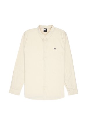 Beige overhemd met lange mouwen, knopen en kraag, met klein zwart logo op het linkerborstzakgebied, plat gelegd op een witte achtergrond.