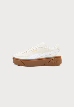 Χαμηλό sneaker Puma σε κρεμ απόχρωση με λευκή πλαϊνή ρίγα και καφέ σόλα, εμφανίζεται από την εξωτερική πλευρά σε απλό φόντο.