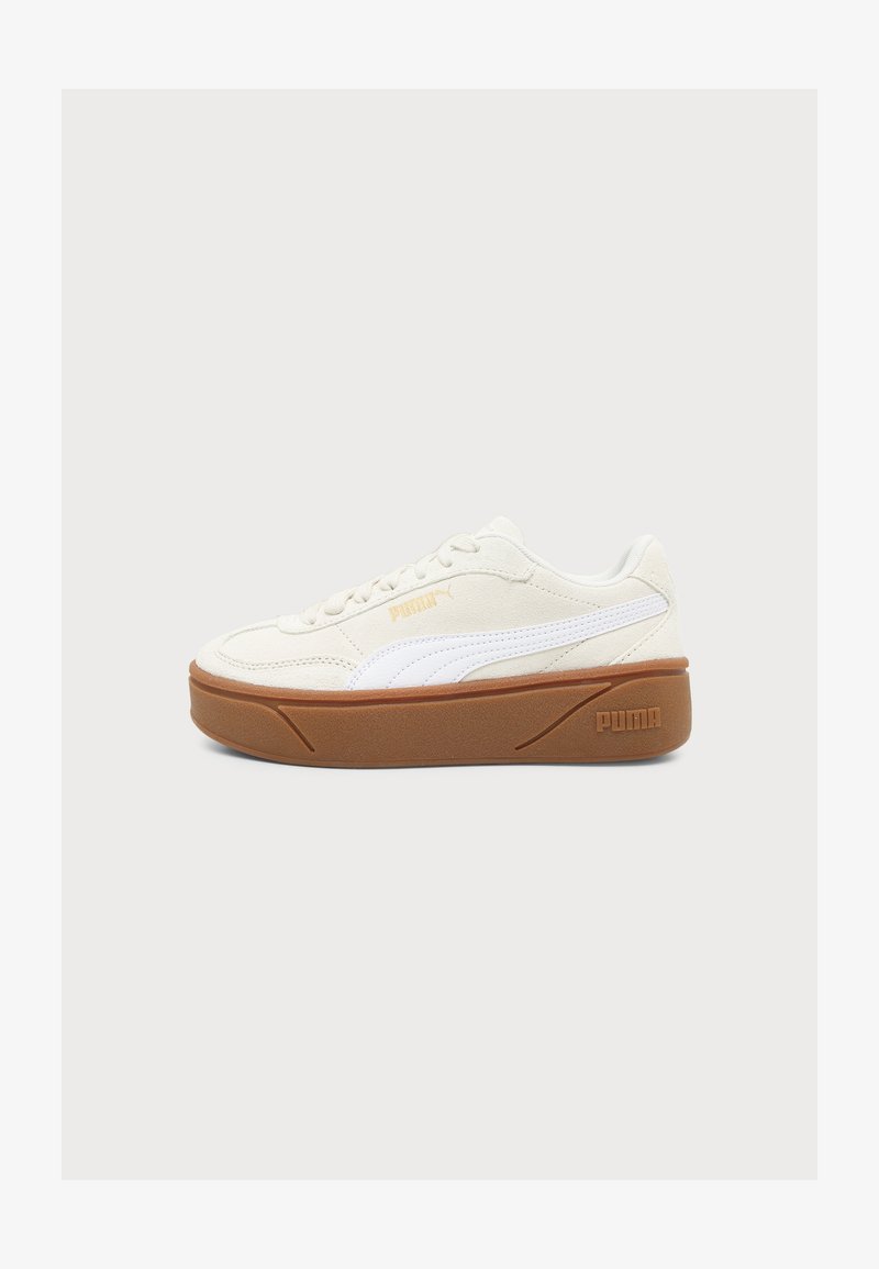 Χαμηλό sneaker Puma σε κρεμ απόχρωση με λευκή πλαϊνή ρίγα και καφέ σόλα, εμφανίζεται από την εξωτερική πλευρά σε απλό φόντο.