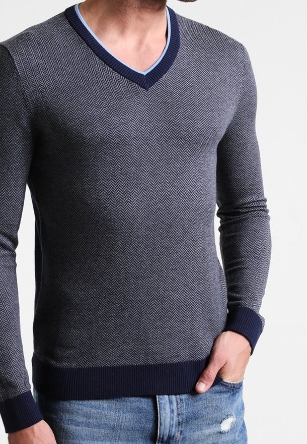 Marinblå v-ringad tröja i fiskbensmönster, tillverkad av texturerat tyg med kontrasterande blå krage och ribbade ärmslut och nederkant.