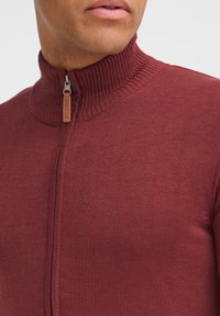 Maglione bordeaux a maglia con colletto alto a coste, zip frontale e tirazip in pelle etichettato "BLEND". Tessuto liscio, design aderente.