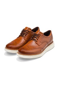 Scarpe eleganti in pelle marrone con dettagli brogue, design con lacci, suola testurizzata e cucitura della suola color crema.