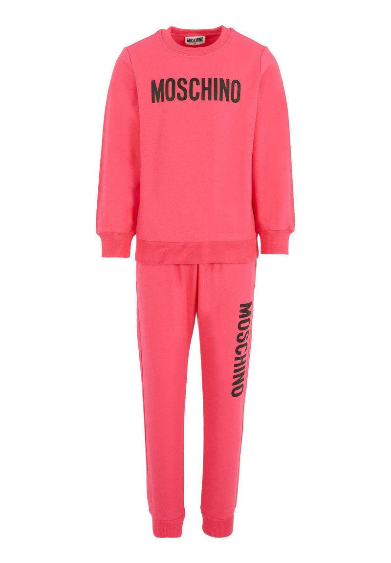 Jasnoróżowa bluza Moschino oraz pasujące dresy z czarnym tekstem logo na klatce piersiowej i lewej nogawce, z ściągaczami przy mankietach i dole.