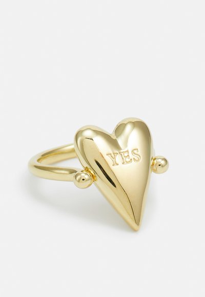 Goldener herzförmiger Ring mit hochglänzender Oberfläche, der in der Mitte den eingravierten Text "JA" und kleine sphärische Akzente am Ringband aufweist.