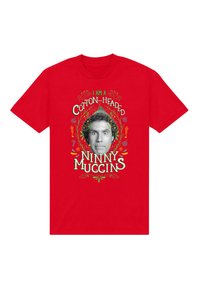 Czerwona koszulka z nadrukiem twarzy i napisem "Jestem bawełnianą głupią miguśką" otoczona świątecznymi dekoracjami.