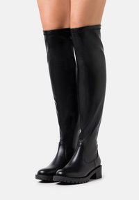 Svarta läderstövlar i höjd med låren med en slät yta, rund tå och texturerad gummisula. Har en elegant, åtsittande design med stickade detaljer.