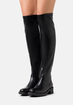 Svarta läderstövlar i höjd med låren med en slät yta, rund tå och texturerad gummisula. Har en elegant, åtsittande design med stickade detaljer.