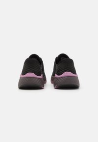 Black athletic shoes with a textured surface, purple accents, and a padded collar, featuring a patterned midsole and a rubber outsole.