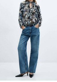 Floral long-sleeve blouse with button details and tie neckline paired with high-waisted blue denim wide-leg jeans and black pointed-toe heels.