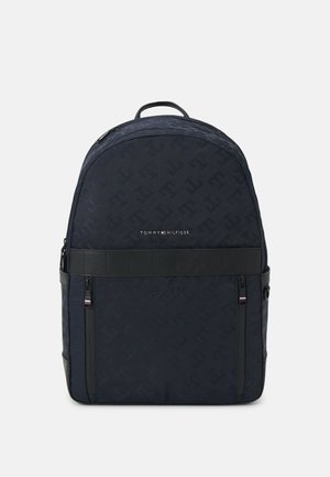 Dunkelblauer Rucksack mit strukturiertem Monogrammmuster, glatten schwarzen Akzenten, einem oberen Tragegriff und einer Fronttasche mit Reißverschluss, die das Markenlogo zeigt.