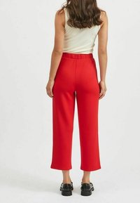 Rode wijde broek met elastische tailleband, gekenmerkt door een gladde stoffen textuur en cropped lengte, gecombineerd met zwarte schoenen.