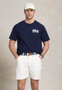 Jūras flotes kokvilnas T-krekls ar "POLO" logo, baltas džins短as ar plānām malām, daudzkrāsains svītrots josta un balts cepure.