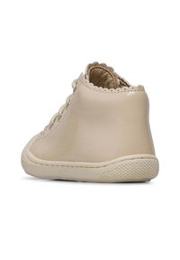 Beige leren enkellaars met decoratieve golfranden, gestructureerde rubberen zool en vetersluiting aan de voorkant. Gladde afwerking met een subtiele glans.