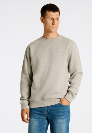 Sudadera gris clara hecha de una mezcla de algodón, con cuello redondo y puños acanalados, combinada con jeans azules. Marca mínima en el pecho.