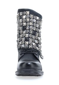 Czarne skórzane botki na kostkę z widocznym designem ozdobnym z dużymi srebrnymi ćwiekami w kształcie piramidy oraz okrągłymi ćwiekami. Widziane sznurowanie i detal zamka błyskawicznego z boku.