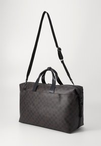 Brown checkerboard-patterned bag with black leather accents, dual top handles, and adjustable strap; rectangular shape with zipper closure.