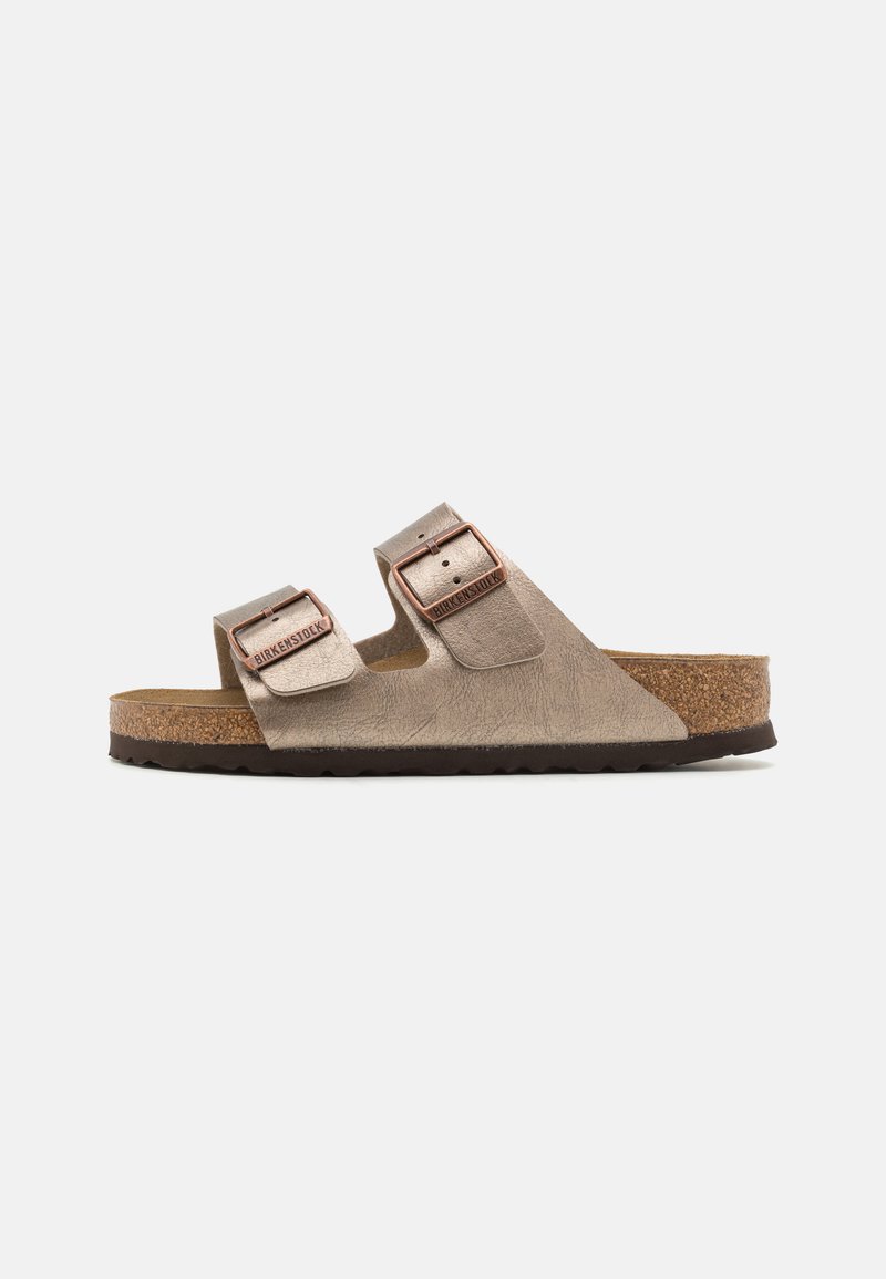 Sandale Birkenstock cu două catarame metalice ajustabile, brâu texturat de culoare bej și talpă din plută, având o talpă din cauciuc maroniu.