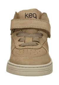 Bruine leren sneaker met een klittenbandsluiting en veters, met geperforeerde details op de neus en een beige rubberen zool.