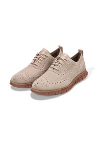 Sneaker in maglia beige con un motivo testurizzato, design con lacci, tomaia in tessuto morbido e suola in gomma flessibile con dettagli scanalati.