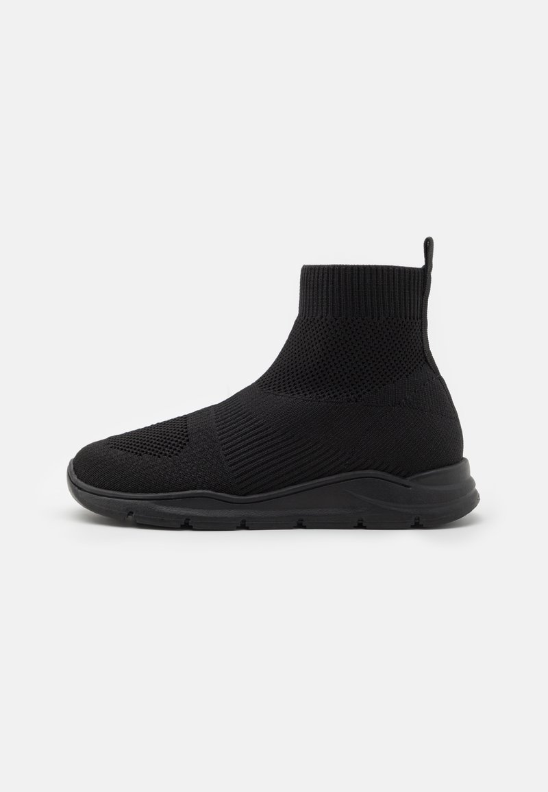 Černé pletené sneakersy po kotníky s texturovaným vzorem, flexibilní podešví a polstrovaným límcem. Obsahuje poutko pro snadné obouvání.