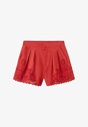 Červené krátke nohavice s vysokým pásom, záhybmi a výšivkami kvetov na vlnitých lemovaných okrajoch, s bočnými vreckami a predným zapínaním.