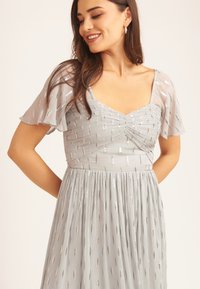 Silver and grey chiffon dress with short flutter sleeves, ruched bodice, and vertical metallic accents; soft texture and A-line silhouette.