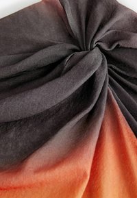 Écharpe en tissu noué présentant un dégradé ombragé du noir à l'orange, fabriquée en matériau doux et texturé. Le design est drapé, mettant en valeur des plis.
